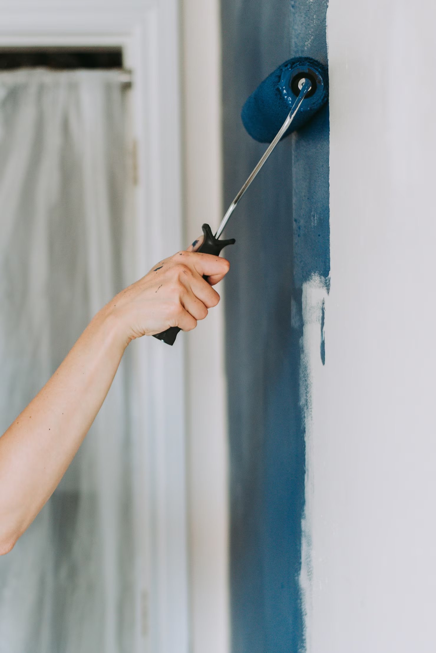 closeup-shot-person-using-paint-rollers-with-color-blue_181624-2451